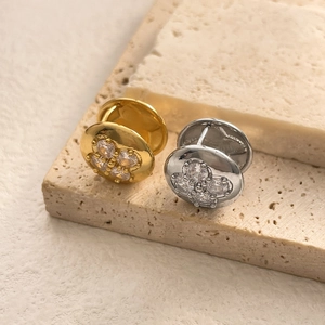 Macro detail of gold and silver flower stud earrings with shimmering zircon inlays