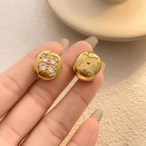 Macro detail of gold-plated flower earrings with sparkling zircons and floral engraving