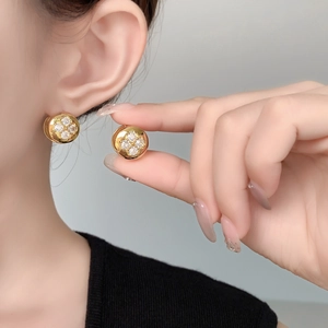 Detailed view of 10mm gold plated round stud earrings with clover zircon inlay on ear