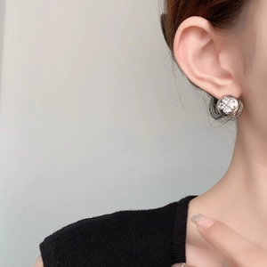 Detailed close-up of a zircon flower earring with gold plating on a model's ear