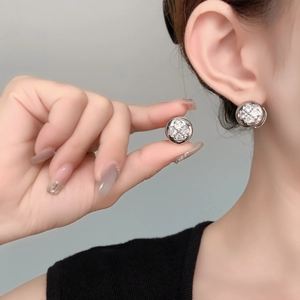 Macro shot of silver flower earrings with zircon stones worn on the earlobe