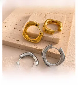 Détail de boucles d'oreilles créoles carrées en finitions or et argent poli