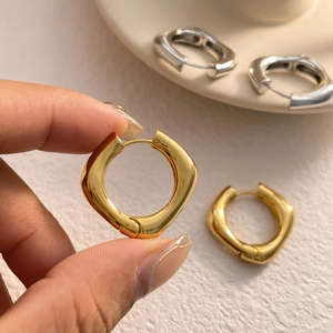 Vue macro de boucles d'oreilles carrées en or et argent avec finition polie miroir