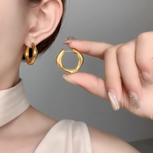 Détail de boucles d'oreilles dorées géométriques avec un design intérieur-extérieur