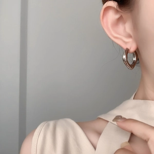 Gros plan de boucles d'oreilles argentées torsadées minimalistes sur une oreille