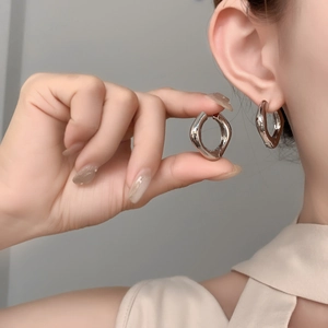 Gros plan de boucles d'oreilles créoles épaisses argentées au fini poli et profil arrondi