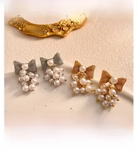 Macro view of gold and silver bow stud earrings with delicate white pearl clusters