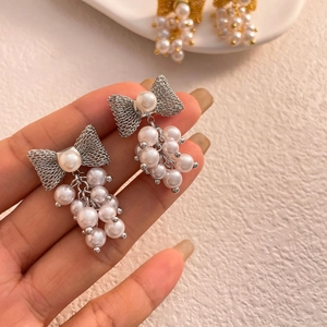 Elegant bow knot pearl drop earrings featuring silver mesh and clustered pearl tassels