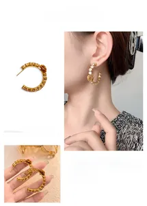 Detail of C-shaped gold-plated hoop earrings with cubic zirconia and metal rose accents
