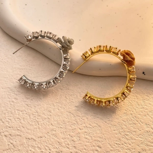 Macro detail of gold and silver C-shaped hoop earrings with zircons and tulle flower