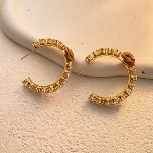 Detailed shot of gold-plated C-shaped hoop earrings with zircons and floral accents
