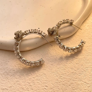 Macro shot of gold and silver C-shaped hoop earrings with zircon stones and metal flower detail