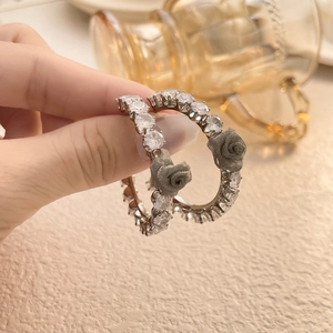 Detailed close-up of zircon hoop earrings featuring grey 3D fabric rose flower accents