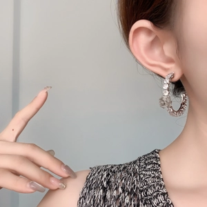 Elegant silver flower hoop earrings with zircon stones worn by a model in a side view