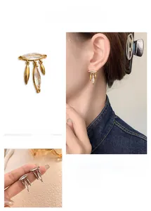 Detail view of leaf tassel earrings with marquise cubic zirconia in gold plating
