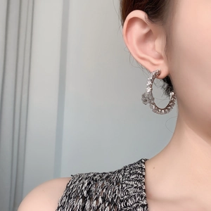 Detail of silver C-shaped hoop earring with a 3D rose flower and cubic zirconia crystals