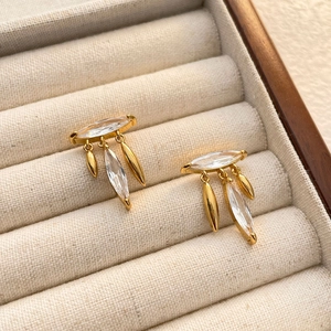 Macro shot of gold-plated leaf tassel earrings with marquise-cut zircon in a jewelry box