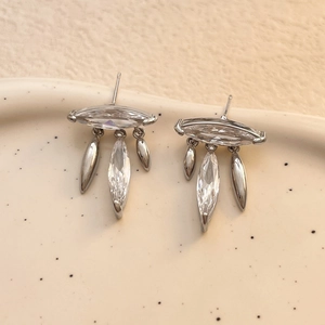 Close-up of silver leaf tassel earrings with marquise-cut zircons on ceramic tray