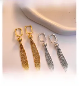 Detail of long metal tassel drop earrings with geometric studs in gold and silver