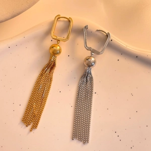 Macro detail of geometric square huggie earrings with long chain fringe in gold and silver