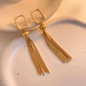 Close-up of golden geometric square earrings with elegant long chain tassel details