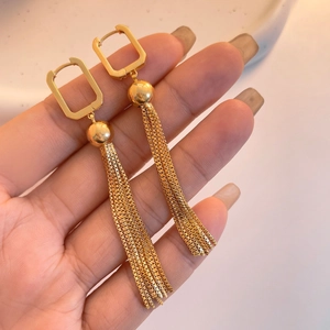 Detail of gold chain tassel earrings featuring square buckle and polished bead accents