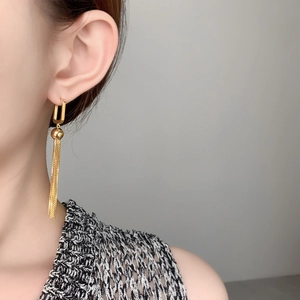 Close-up of elegant gold geometric square earrings with long chain fringe on a model