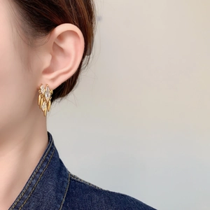 Close-up of gold tassel earrings with marquise zircon stones worn by a model