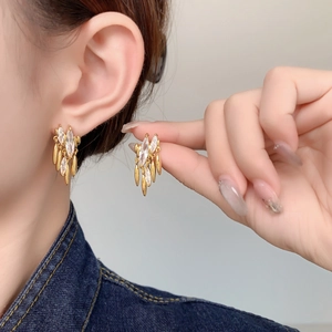 Macro shot of 18K gold tassels earrings with marquise zircon stones on model