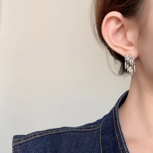 Close-up of sparkling marquise zirconia tassel earrings on model with denim outfit
