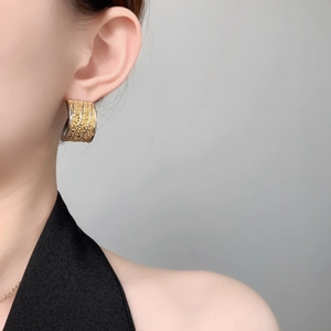 Detailed view of two-tone C-shape earrings with lava texture on a female model