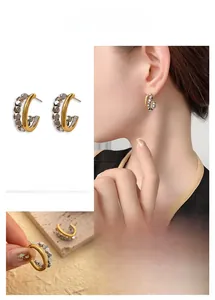 Close-up of geometric C-shaped hoop earrings with two-tone gold and silver cubes