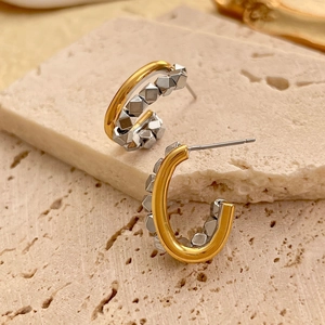 Macro detail of two-tone C-shaped earrings with gold finish and silver cubic studs