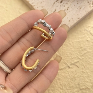 Detailed close-up of two-tone geometric earrings with gold and silver cubic elements