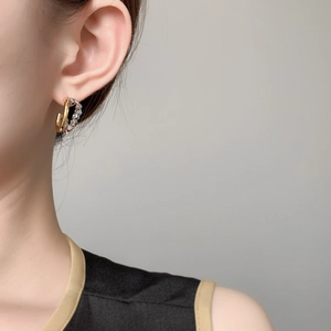Close-up of dual-tone interlocking cube earrings with gold and silver geometric hoops