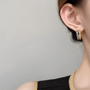 Detail of two-tone C-shaped earrings with gold smooth and silver textured geometric rings