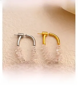 Detail of U-shaped gold and silver earrings featuring clear crushed zircon stones