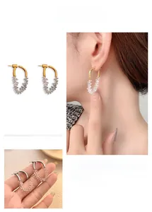 Detailed view of U-shaped stone drop earrings in gold and silver finish with crystal chips