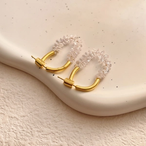 Close-up of gold earrings with sparkling clear crystal beads on a stylish tray