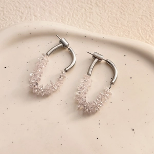 Detail of silver drop earrings with clear cubic zirconia on a beige ceramic tray