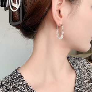 Elegant U-shaped silver earrings with sparkling white crystals shown on a female model