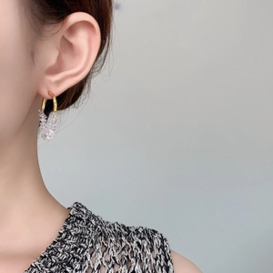 Detailed close-up of sparkling white zircon drop earrings worn by a model on a gold hook