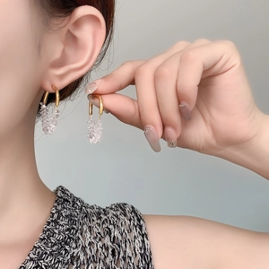 Detail of elegant gold U-shaped hook earrings with clear cubic zirconia drop on a model