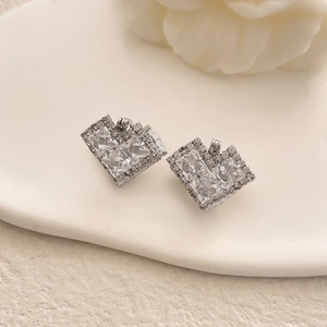 Detailed view of silver heart-shaped stud earrings with cubic zirconia on a ceramic plate