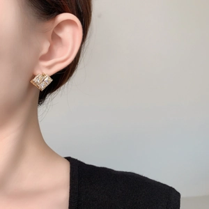 Detailed close-up of a 18K gold plated rhombic earring with micro-paved cubic zirconia