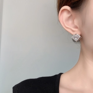 Close-up of elegant square zircon earrings in silver finish worn on ear model