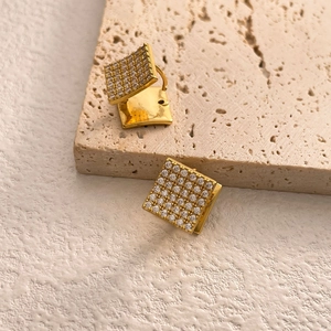 Detailed close-up of square pavé zircon earrings in 18K gold plating on textured stone
