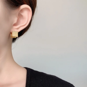 Macro shot of gold square stud earrings featuring micro-pave clear zircon stones