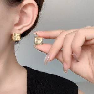 Detail showing high-shine gold square hoop earrings with micro-paved zircons on ears