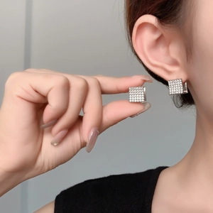 Macro shot of silver square micro-pave zircon earrings held between fingers